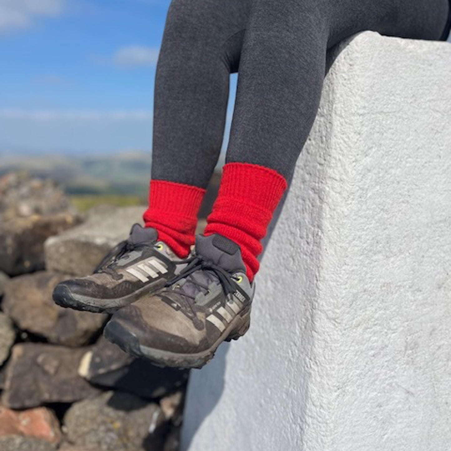 Red ankle-length Capricorn Mohair Socks worn with walking shoes on a summit in the UK hills – warm, breathable and ideal for hikes