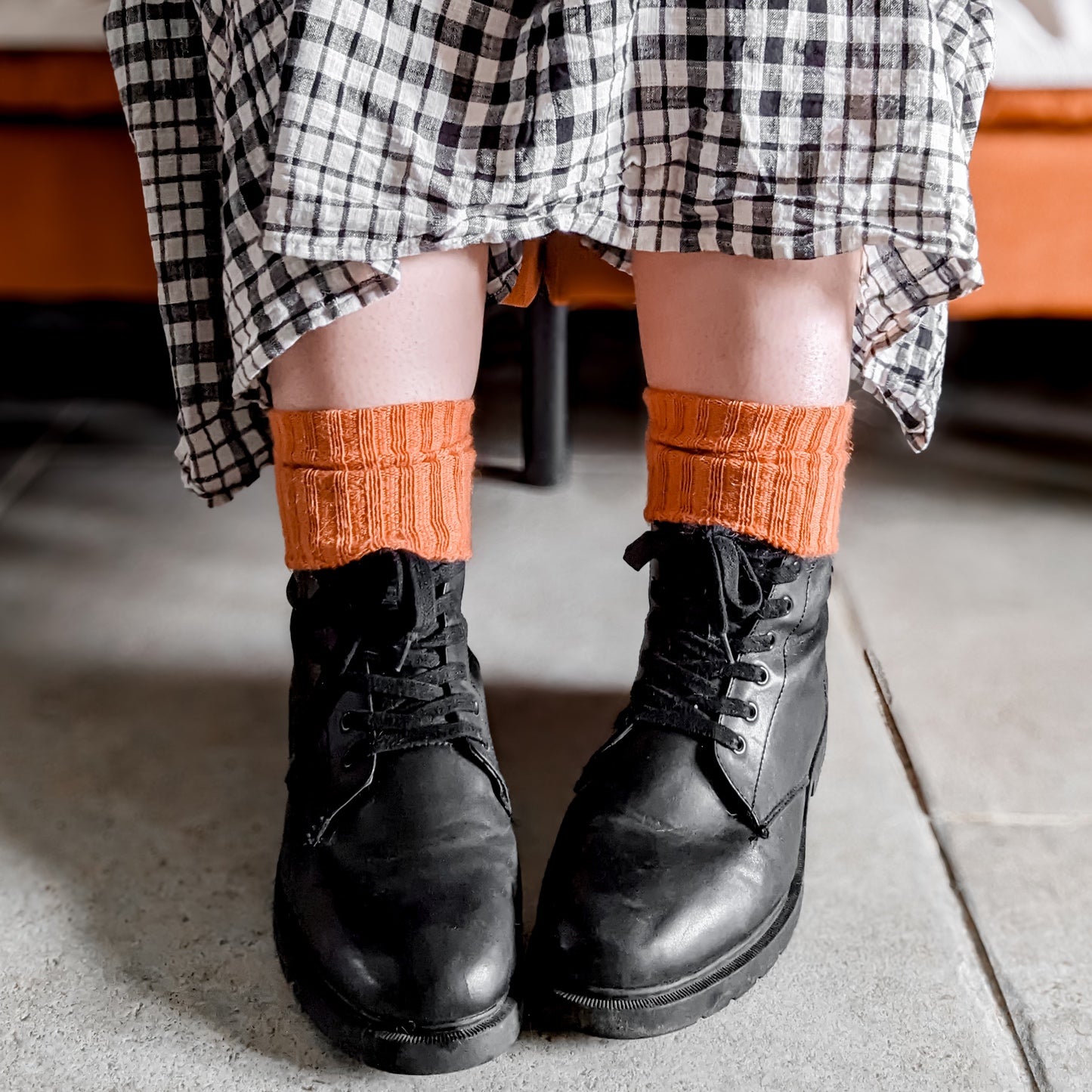 Burnt orange Sussex-style Capricorn Mohair Socks with textured knit, styled with boots and a checked dress – bold, cosy everyday socks with flair