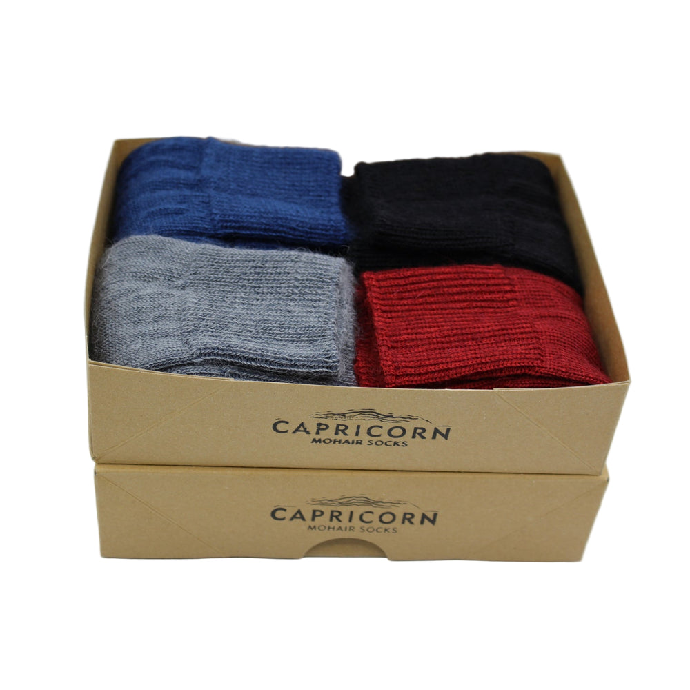 
                      
                        Box of Capricorn mohair socks in blue, grey, black and won a white background
                      
                    