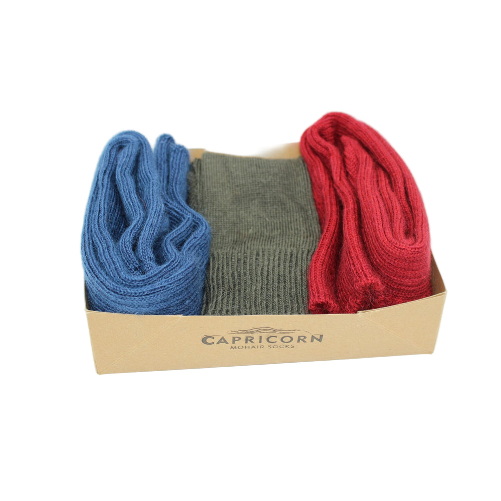 
                      
                        Three pairs of Mohair socks in blue, green, and red in a gift box with 'Capricorn' branding - A present for the Gardener
                      
                    