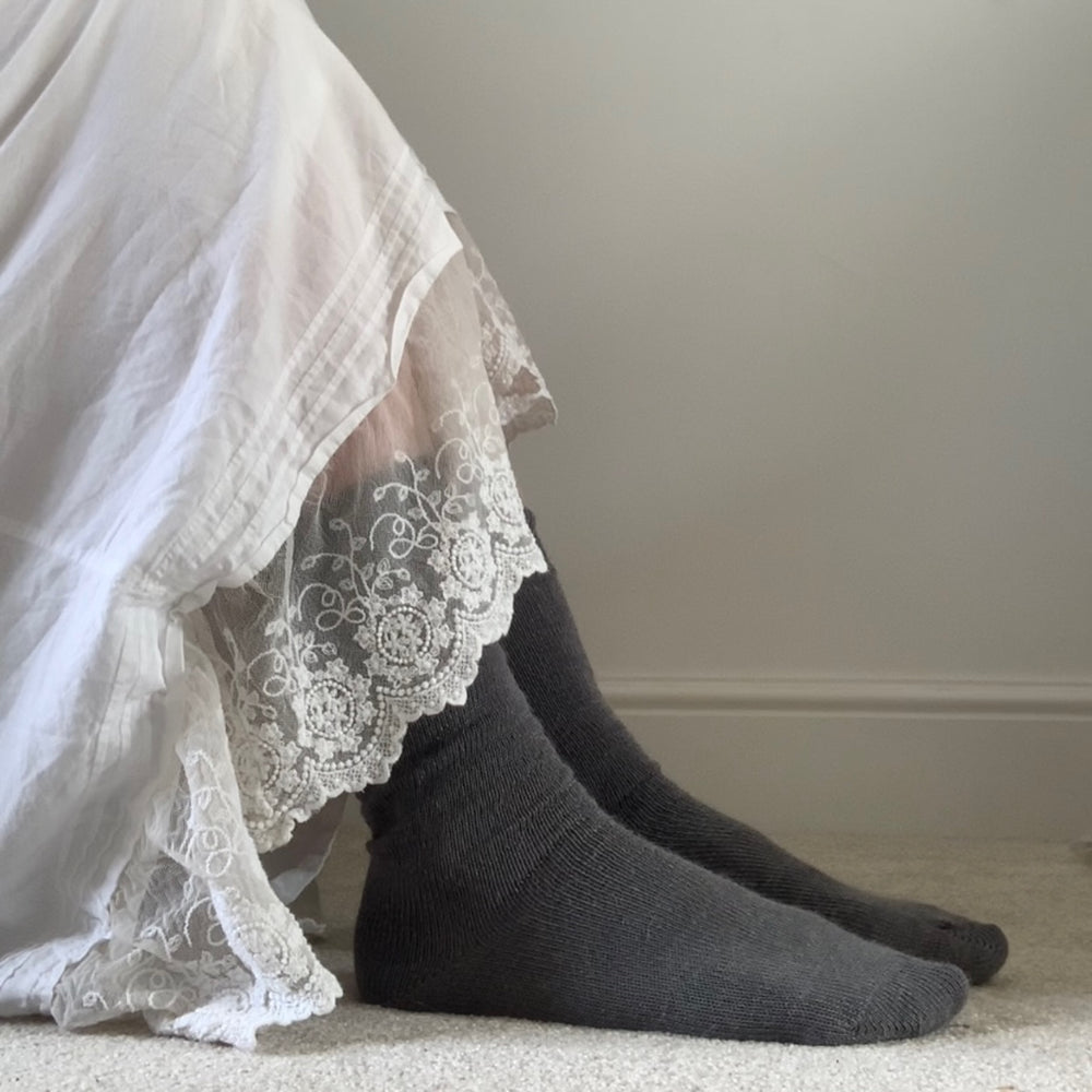 
                      
                        Grey Surrey-style Capricorn Mohair Socks worn indoors with a lace-trimmed white dress – soft, cosy everyday socks for home comfort
                      
                    